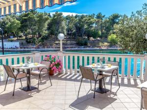 eine Terrasse mit Tischen und Stühlen neben einem Pool in der Unterkunft Apartments & Rooms Milcetic M in Malinska