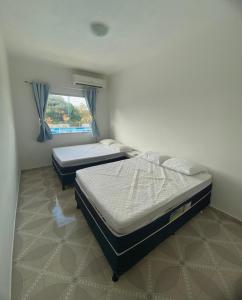 two twin beds in a room with a window at Cacao's Guaibim Residence in Valença