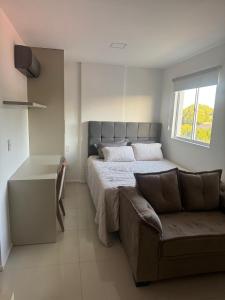 een slaapkamer met een bed, een bank en een raam bij Studio V Ininga - 610 in Teresina