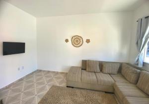 a living room with a couch and a clock on the wall at Cacao's Guaibim Residence in Valença
