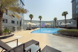 Una piscina con palmeras y un edificio. en Elegant Studio apartment in Avanti Tower Business Bay, en Dubái