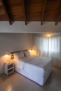 a bedroom with a white bed and a window at Pousada Aromas do Vale in Chapada dos Guimarães