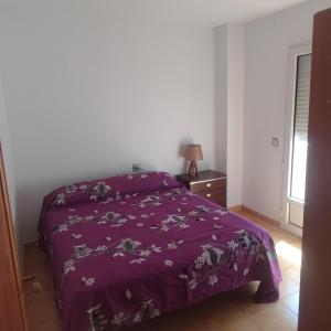 a bedroom with a bed with a purple blanket at Casa costacabana in Almería