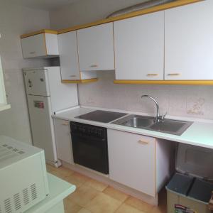 a kitchen with white cabinets and a sink and a refrigerator at Casa costacabana in Almería