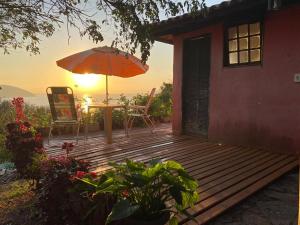 a wooden deck with a table and an umbrella at Bangalô Pontal do Atalaia com piscina para casal ou família in Arraial do Cabo