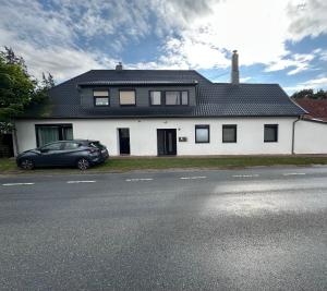 a white house with a car parked in front of it at Ferienwohnung auf dem Land in Grethem