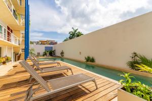 an outdoor deck with chairs and a swimming pool at Duplex w Rooftop Plunge Pool – Walk to Beach in Playa del Carmen