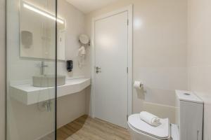 a white bathroom with a toilet and a sink at Vila Baleira Residence in Funchal