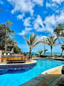 a swimming pool with palm trees and the ocean at SR Sunset in São Sebastião