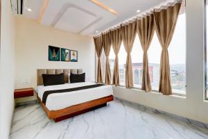 a bedroom with a bed and large windows at HOTEL O NIRVANA in Bhilai