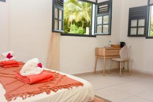 a bedroom with a bed and a desk and windows at Lisalyne in Le Moule
