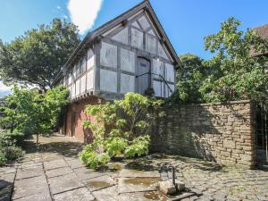 an old house with a stone wall and a tree at The Coach House in Church Stretton