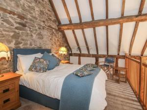 a bedroom with a bed and a stone wall at Courtyard Cottage in Church Stretton