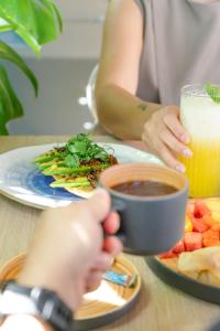 Eine Person, die eine Tasse Kaffee und einen Teller mit Essen hält. in der Unterkunft Hotel Once22 in Sabaneta