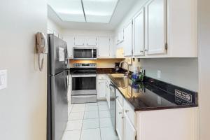 a kitchen with white cabinets and a stainless steel refrigerator at Phoenix I 1142 in Orange Beach +23 photos
