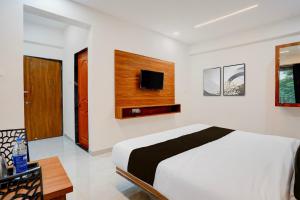 a bedroom with a bed and a tv on a wall at Hotel O Avaanti in Pune