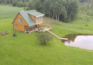 una pequeña casa en una colina junto a un estanque en Aratsaare Holiday home, en Kõpu