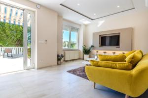 a living room with a yellow couch and a tv at Apartments & Rooms Milcetic M in Malinska