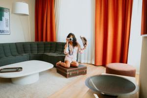 穆尔滕KORNHAUS Boutique Hotel的一个小女孩坐在客厅里的一个箱子上