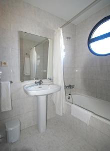 a white bathroom with a sink and a bath tub at Hotel Marinetto in Chauchina