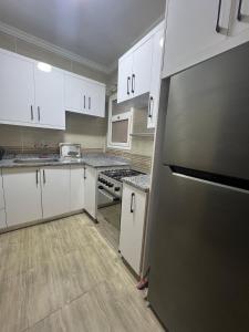 une cuisine avec des armoires blanches et un réfrigérateur en acier inoxydable dans l'établissement Cozy cheap apartment, à Burg el-Ḥudûd
