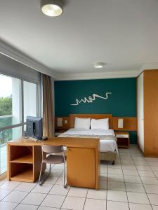 a bedroom with a bed and a desk with a computer at Praia do Canto Apart Hotel - Vista para o Mar 102A in Vitória