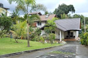 a white house with palm trees and a driveway at Staysia Guest in Kandy