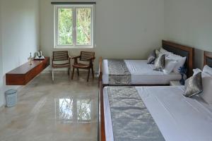 a bedroom with two beds and a desk and a table at Staysia Guest in Kandy