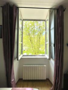 a window in a room with a radiator and a tree at Le Studio des Demoiselles in Rochefort +11 photos