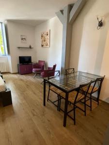 a living room with a glass table and chairs at Le Studio des Demoiselles in Rochefort