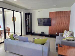 a living room with two couches and a flat screen tv at Burgos Cuernavaca Pool Terrace & Garden in Temixco