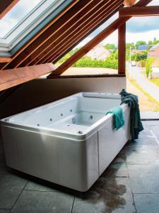 a large white bath tub in a room with a window at Au Vent des Blés in Incourt