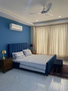 a bedroom with a large bed with blue walls at Spacious & Comfy 2BR in Bahria Enclave in Islamabad