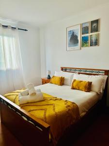 Un dormitorio con una cama grande con almohadas amarillas. en Ocean Gardens, en Caniço