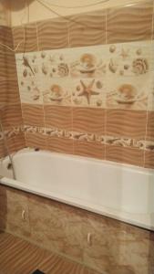 a white bath tub sitting in a bathroom at Квартира по суточно in Taraz
