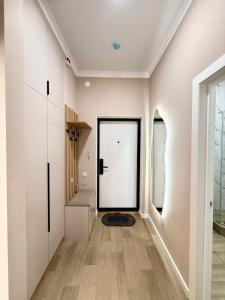 a hallway with a white door and wooden floors at Светлая и уютная квартира с видом на горы, рядом с ТРЦ in Almaty