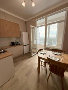 a kitchen with a table and chairs and a kitchen with a window at Светлая и уютная квартира с видом на горы, рядом с ТРЦ in Almaty
