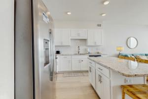 Una cocina con gabinetes blancos y un refrigerador de acero inoxidable. en Sea Glass 203- No Worries, en Gulf Shores