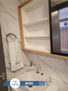 um lavatório de casa de banho com um espelho e uma toalha em Makani Beach Flat Campas #102 - Frente Norte Alto Padrão em Tamandaré