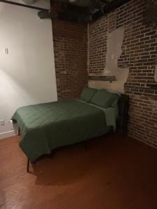 a bedroom with a green bed in a brick wall at The hancock loft in Philadelphia