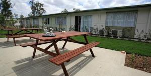 una mesa de picnic y bancos en un patio en Swag Motel, en Middlemount