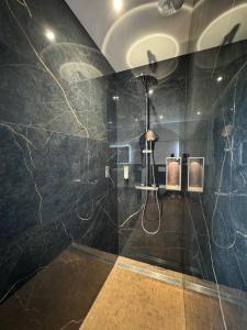 a bathroom with a shower with black marble walls at L'Orée Lodge in Montcornet