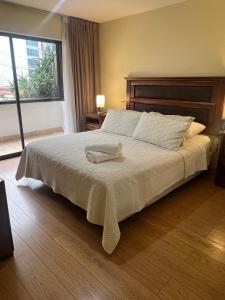 Un dormitorio con una cama con una toalla encima. en Departamento Coyancura, en Santiago