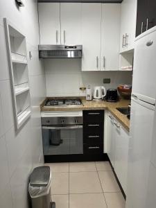 Una cocina con gabinetes blancos y un horno de estufa. en Departamento Coyancura, en Santiago