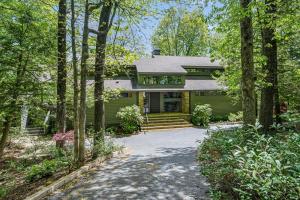 a green house with a driveway in the woods at Heaven and Earth - Luxury Accomodations, Breathtaking Mountain Views, Game Rooms + More! in Jasper