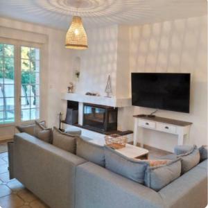 a living room with a large couch and a flat screen tv at VILLA 1900 Bord de mer piscine SPA Nordique in Saint-Brevin-les-Pins