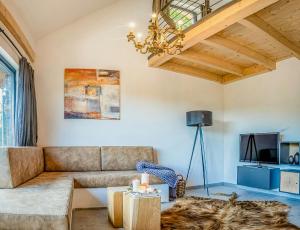 a living room with a couch and a chandelier at Modern Chalet With Sauna Near Thuringian Forest in Zella-Mehlis