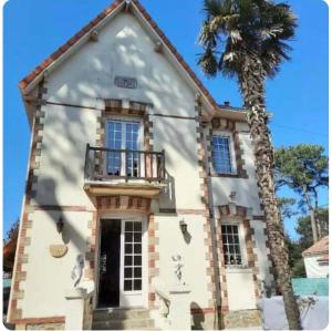 a building with a palm tree in front of it at VILLA 1900 Bord de mer piscine SPA Nordique in Saint-Brevin-les-Pins