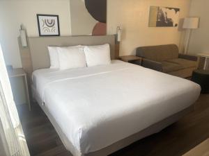 a bedroom with a white bed and a chair at Spark by Hilton Lakewood Denver Southwest in Lakewood