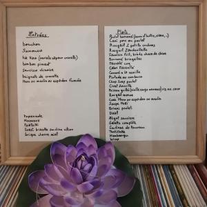 a menu with a purple flower and a plate of food at Kaze Paradis in Saint-Pierre